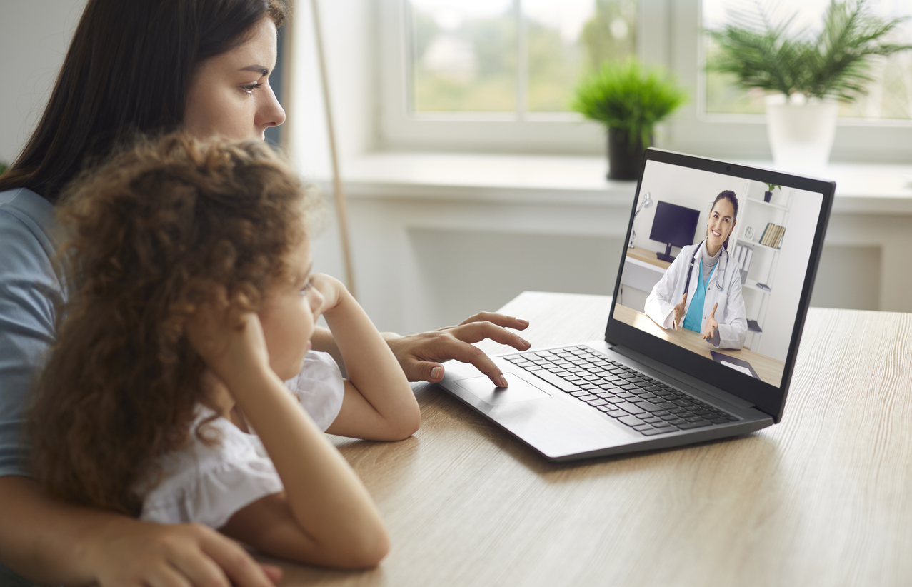 Mother and child speaking to medical professional over a telehealth appointment.