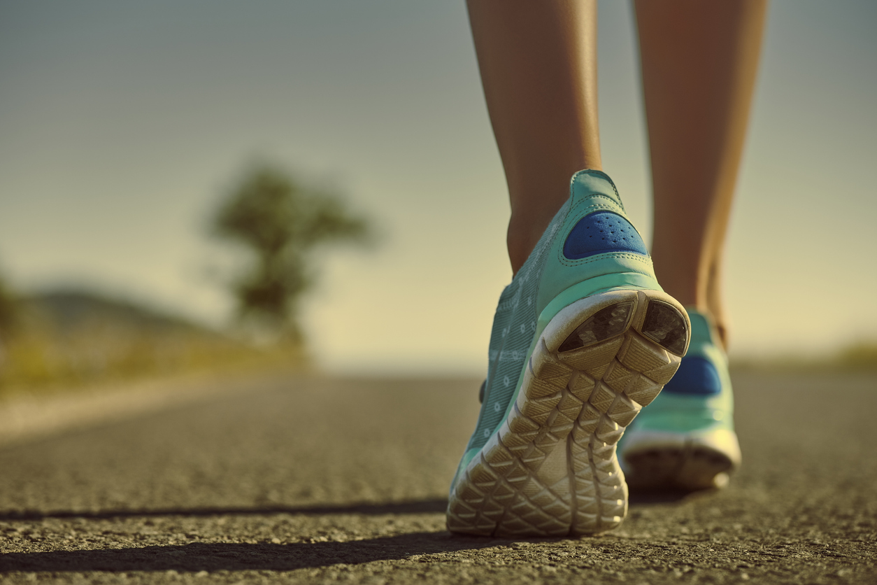 Runner's feet and shoes on a paved road